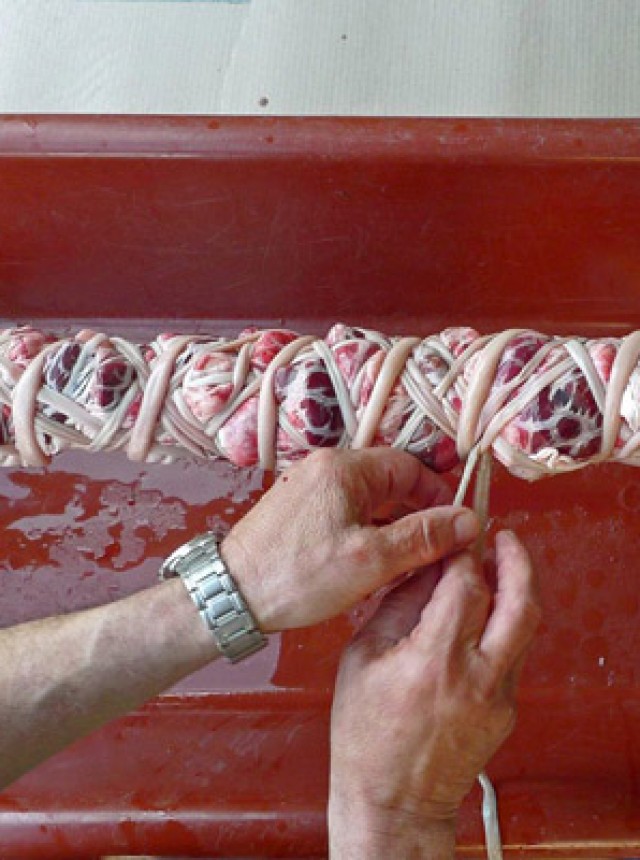 Several layers of very slippery intestines are carefully rolled around the innards.  They will become crackling and delicious, keeping the pieces moist.